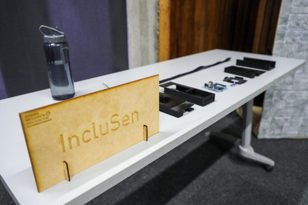 Fotografía del prototipo de IncluSen, con todos sus implementos en una mesa junto a un letrero que dice IncluSen. 