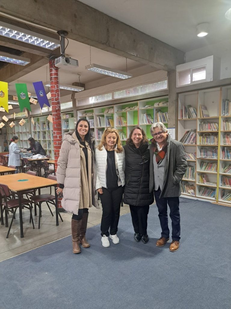 Fotografía de la biblioteca del Colegio San José de Lampa. Al centro de la foto, se encuentran de izquierda a derecha la directora de prekínder a sexto básico, Alejandra Pastén, la cocreadora de MARKO-D Annemarie Fritz, la directora de media Elena González, y el director de CEDETi Ricardo Rosas. Al fondo de la imagen se ven libros en estantes, y mesas con personas utilizándolas.